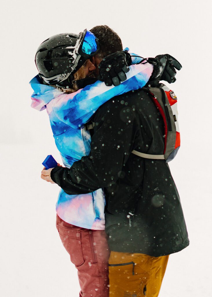 Newly engaged couple hugging on a snowy Vail ski run after a surprise proposal