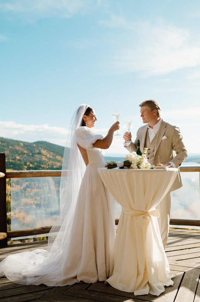 Bride and groom toasting during an outdoor mountain wedding, a joyful moment to consider when choosing a wedding photographer.