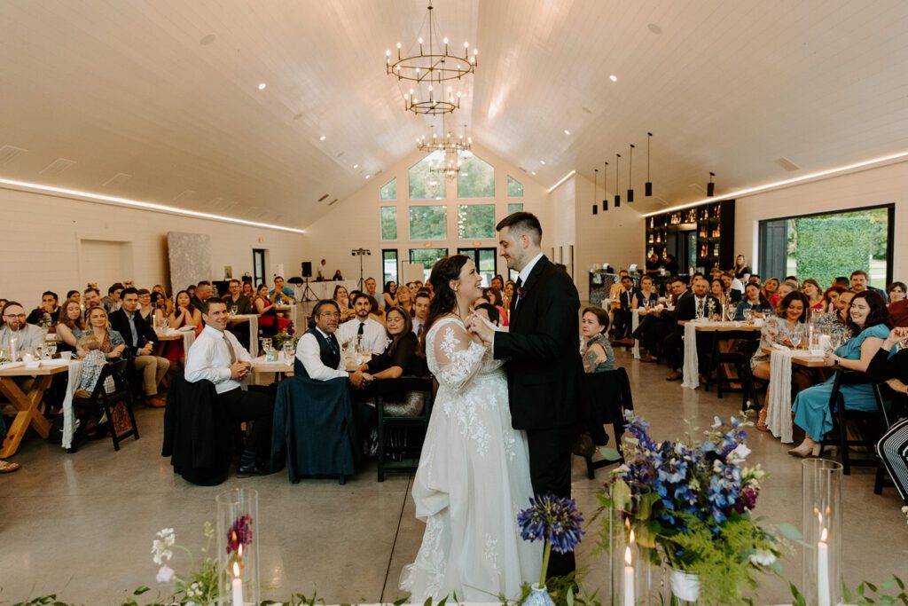 A bride and groom sharing a reception moment indoors, illustrating why you should select a wedding photographer who can prove their technical skill and consistency in low-light environments.
