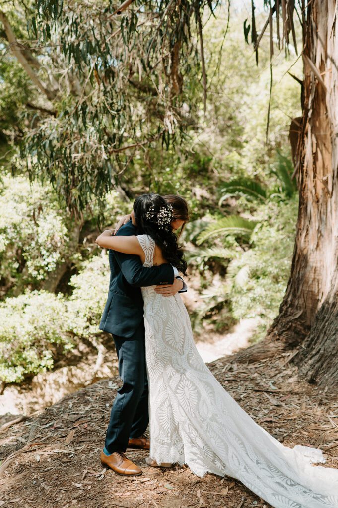Couple embracing beneath the trees during their wedding portraits, showcasing candid wedding photography in a natural outdoor setting.