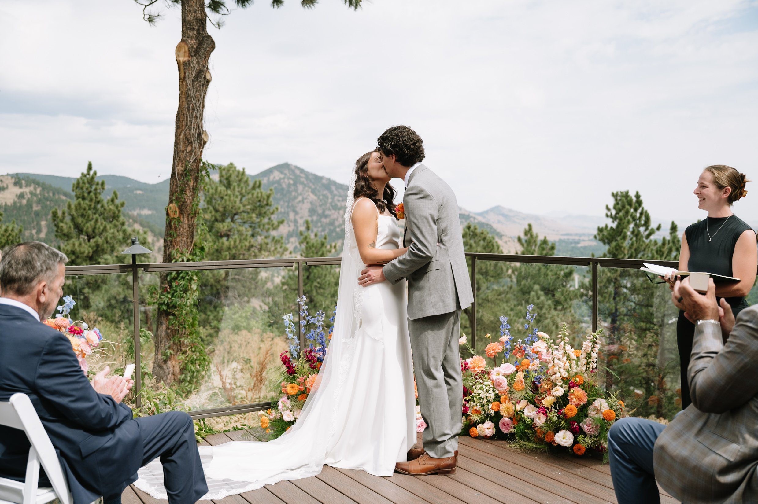 Couple sharing their first kiss during an outdoor mountain ceremony, a perfect example of the best time to get married in Colorado with clear skies and panoramic views.