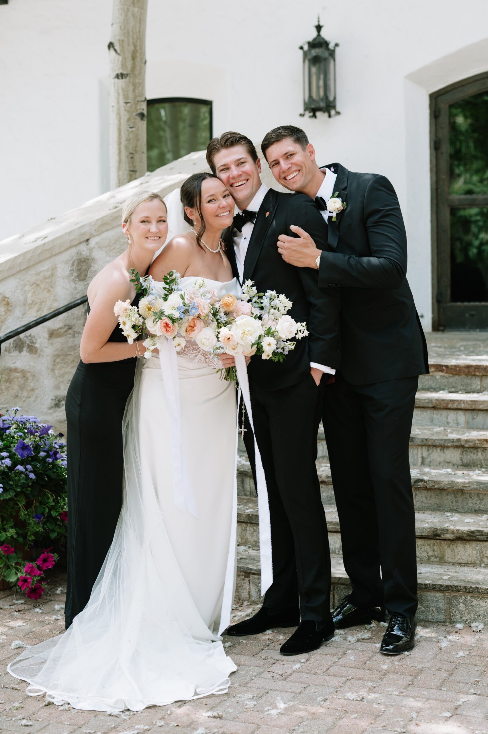 Wedding party gathered on stone steps for a joyful portrait, a classic outdoor scene that reflects the best time of year to get married in Colorado with clear weather and beautiful light.