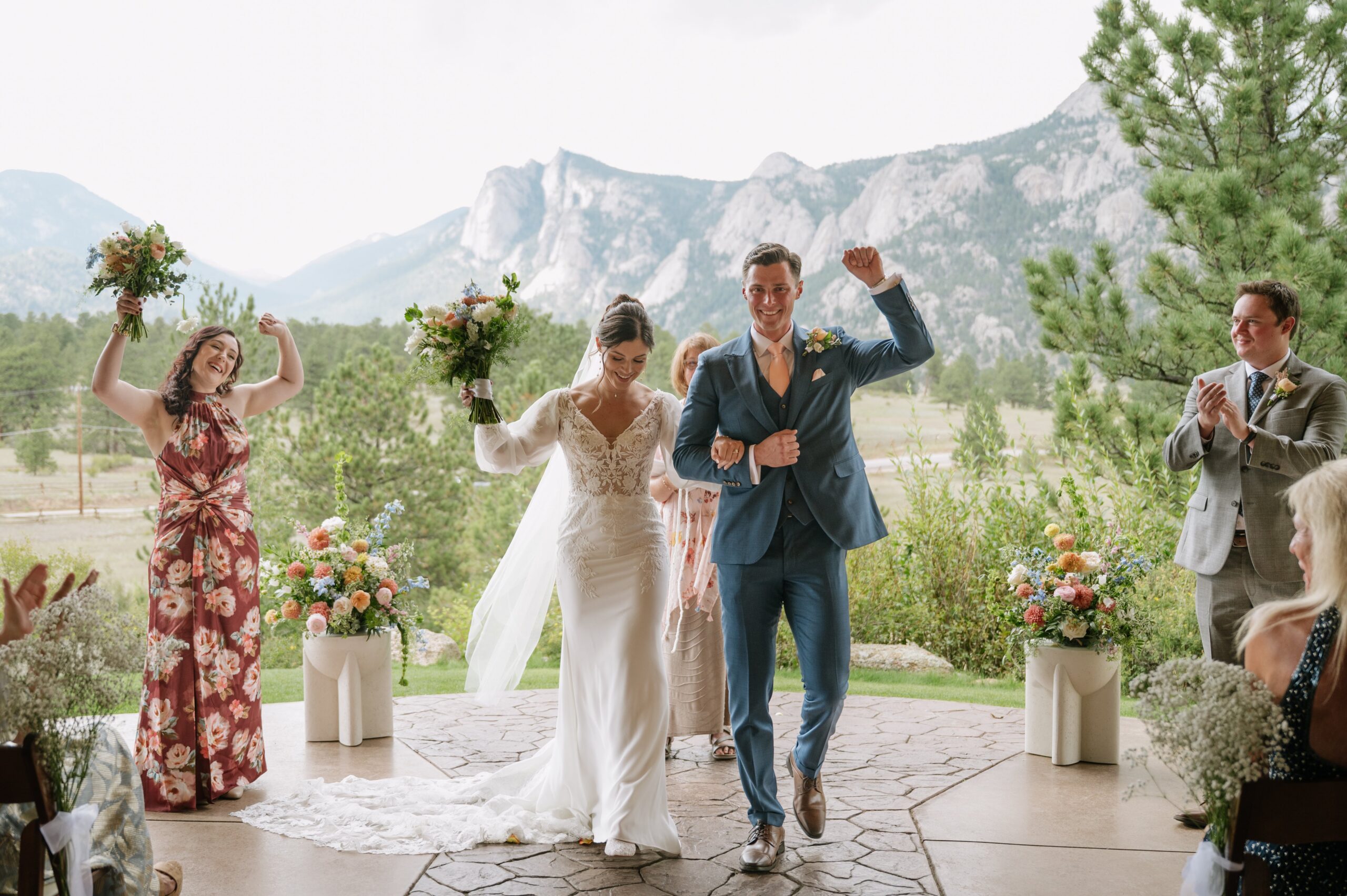Joyful ceremony exit with the couple cheering and guests applauding against a mountain backdrop, representing the best time to get married in Colorado for unforgettable outdoor celebrations.