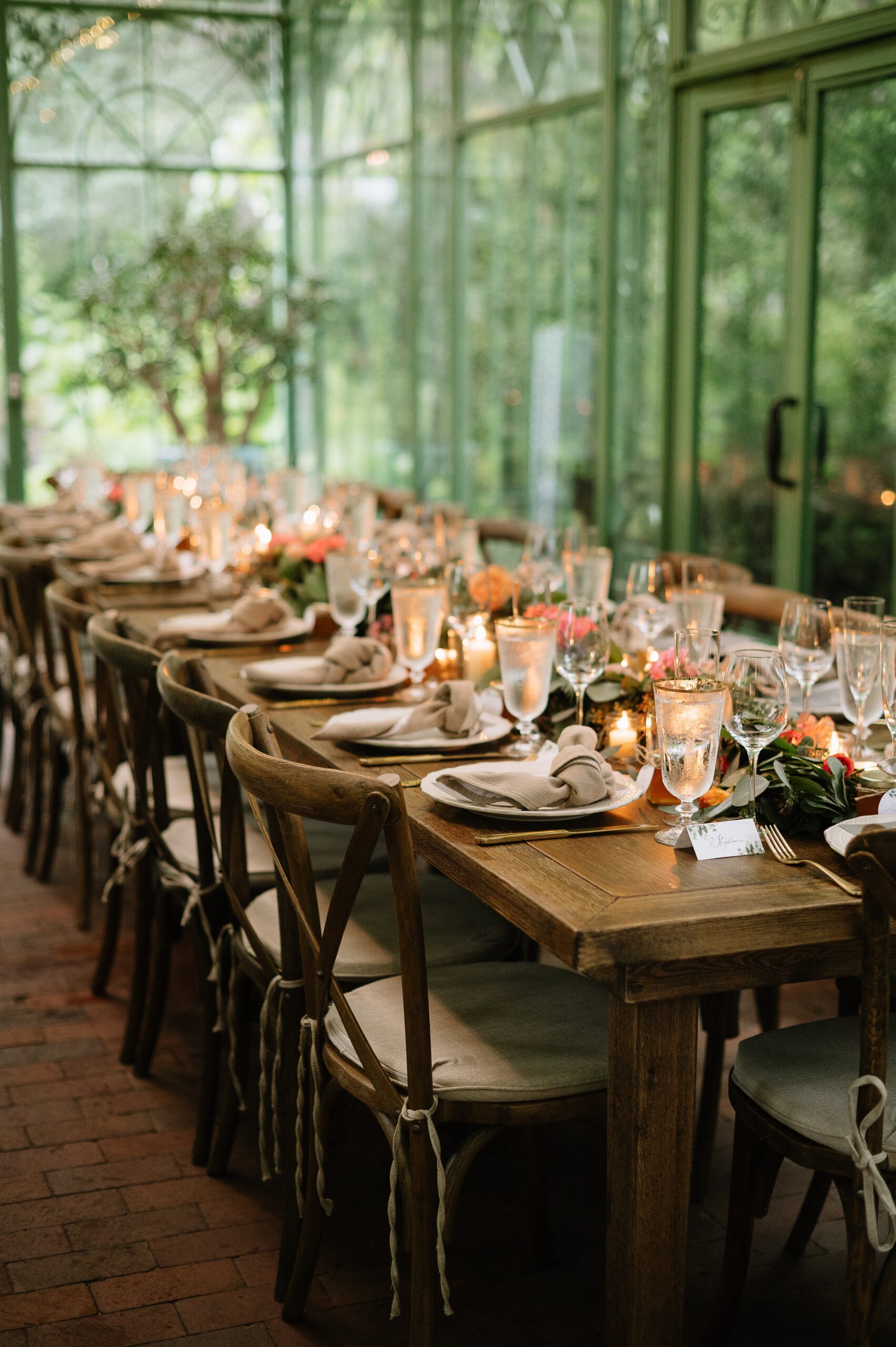 Warm, candlelit reception table inside a Denver Botanic Gardens wedding venue, featuring wooden tables, soft linens, and floral centerpieces.