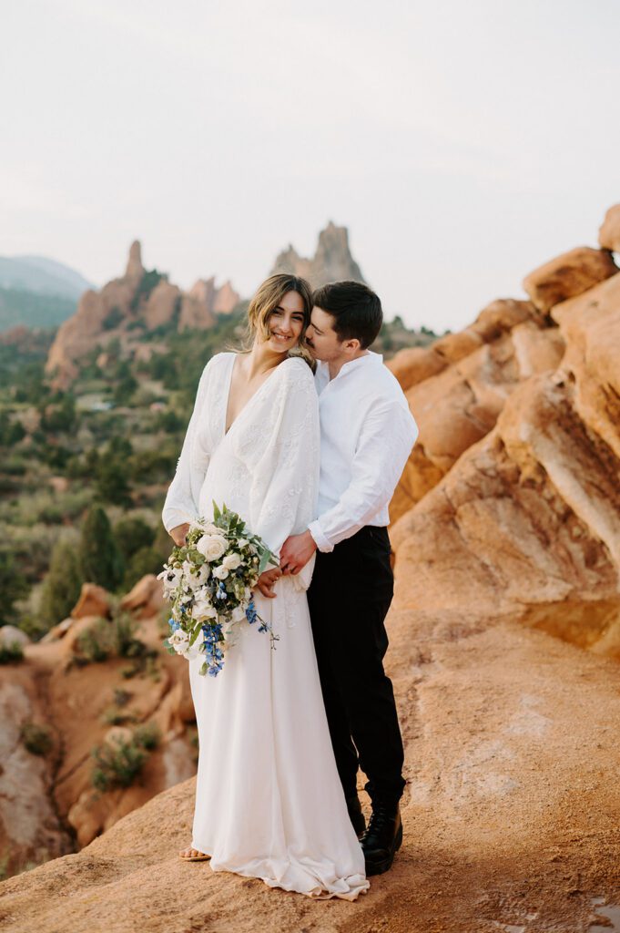 Romantic portrait of a couple on a rocky overlook at golden hour at a small outdoor wedding venue in Colorado. 