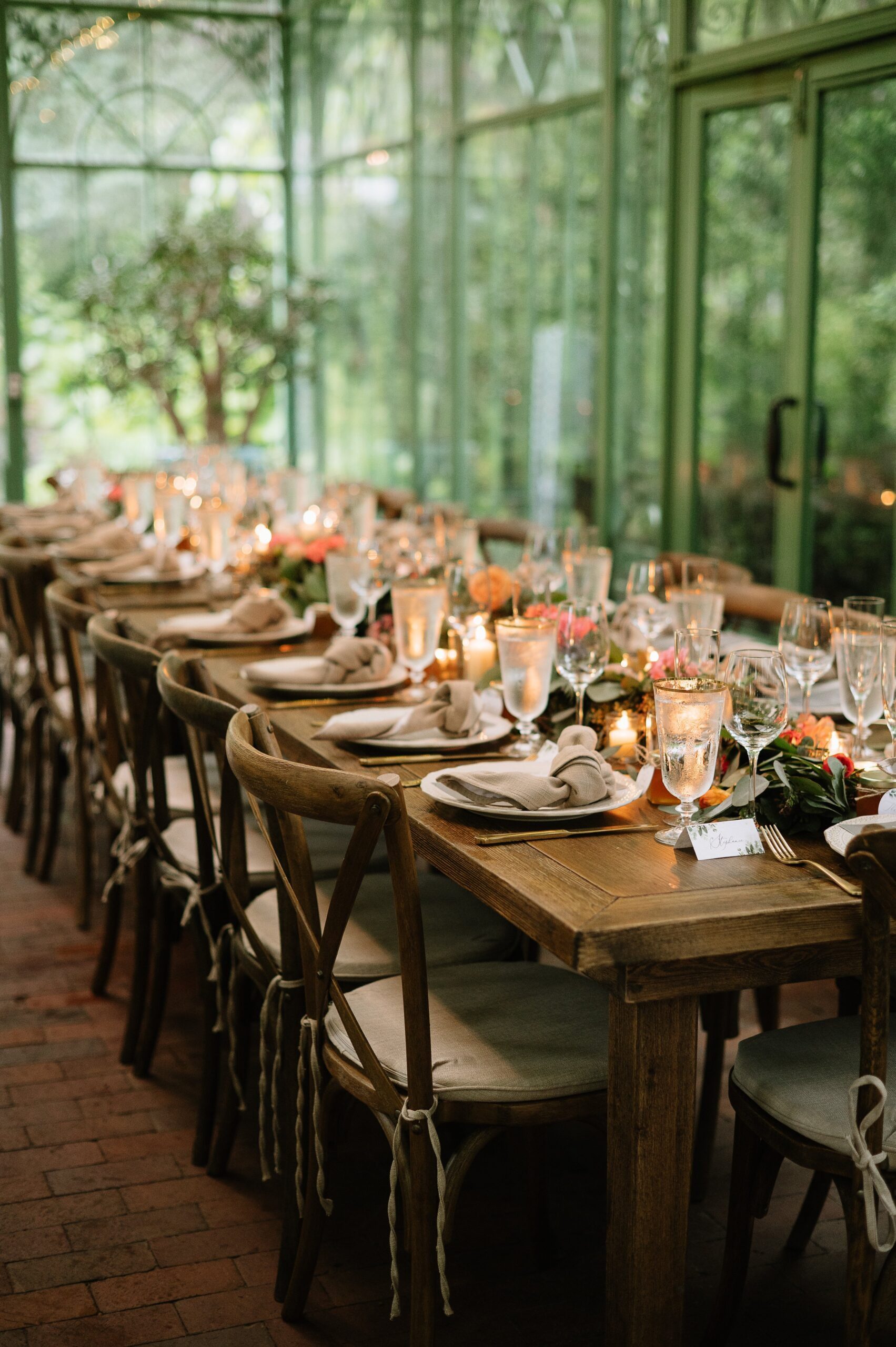 Reception table styled with candles and florals inside a greenhouse at a small wedding venue in Colorado mountains. 
