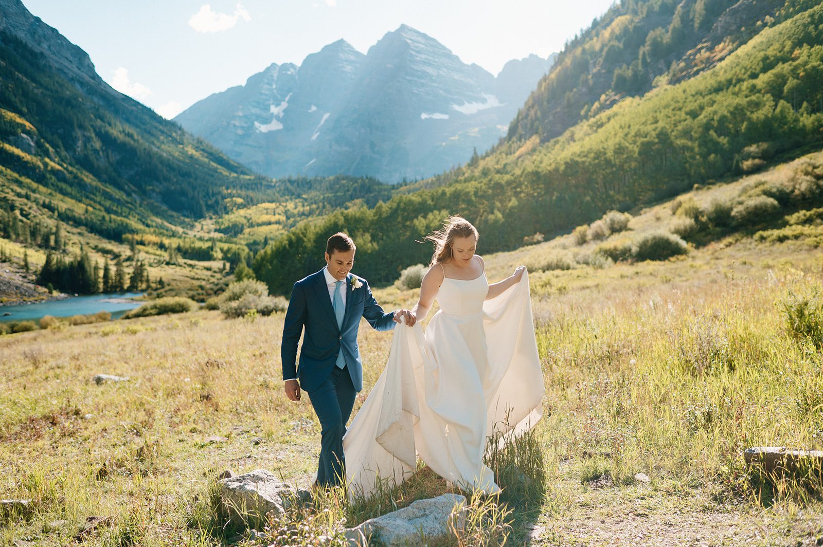 newlywed couple walks hand-in-hand in front of gorgeous backdrop at a small wedding venue in Colorado mountains.