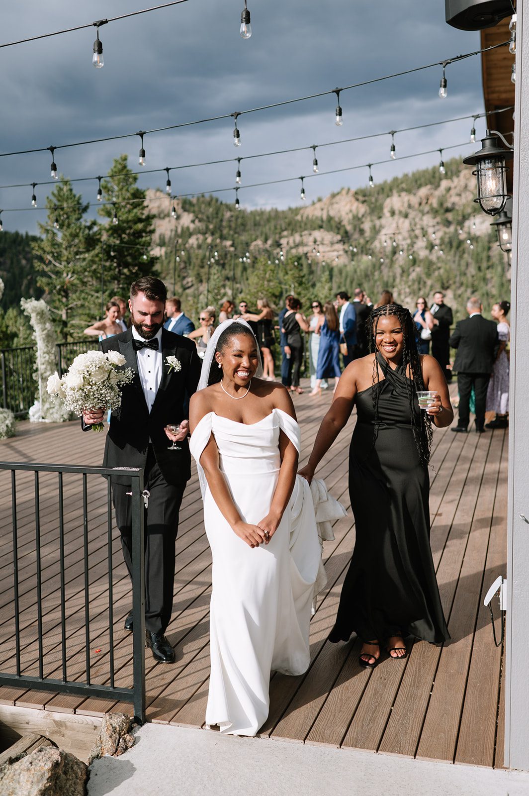 bride, her groom, and her bridesmaid walking off the wooden cocktail hour deck during their north star gatherings wedding