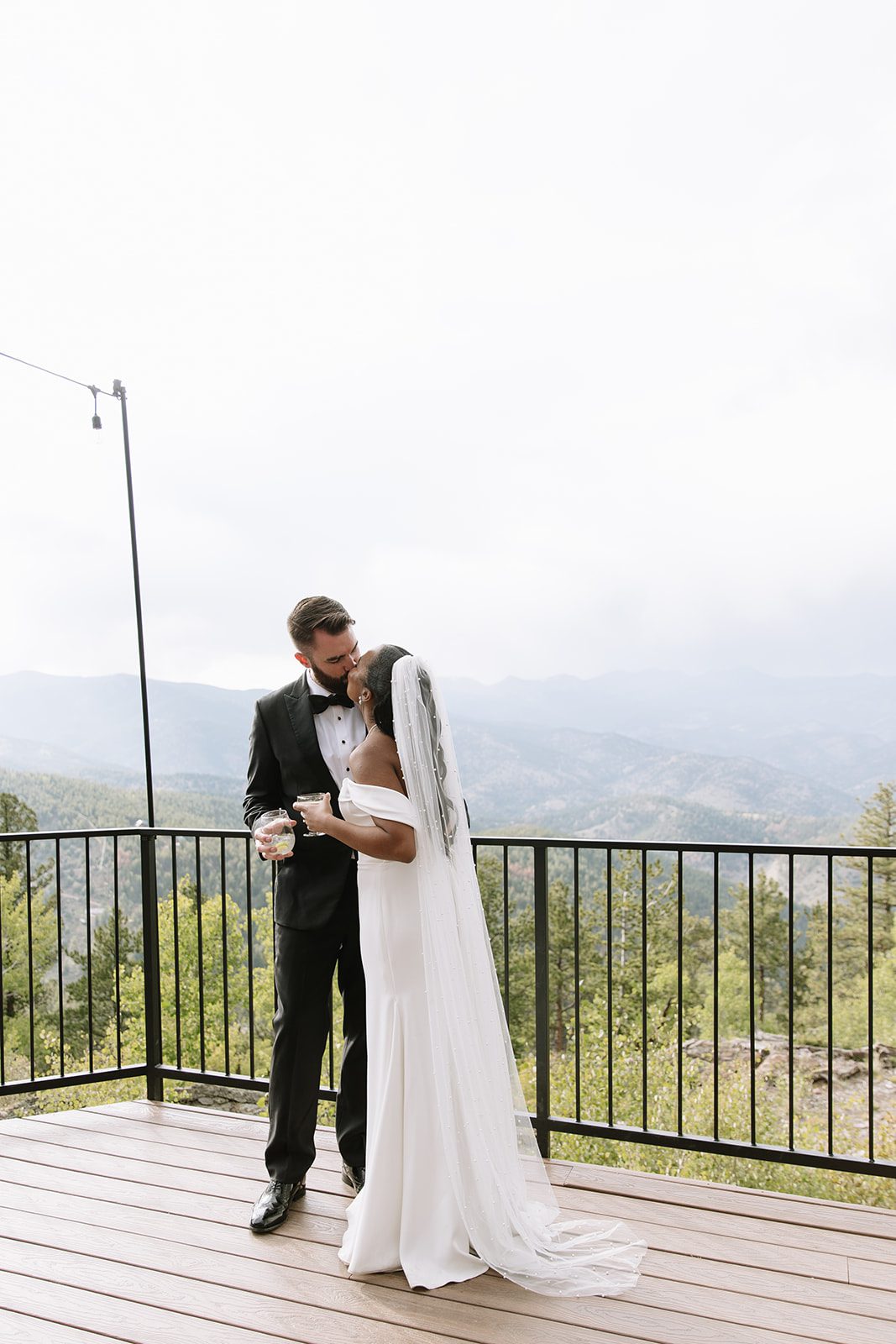 north star gatherings photo of a bride and groom kissing on a wooden deck with the mountain as their backdrop