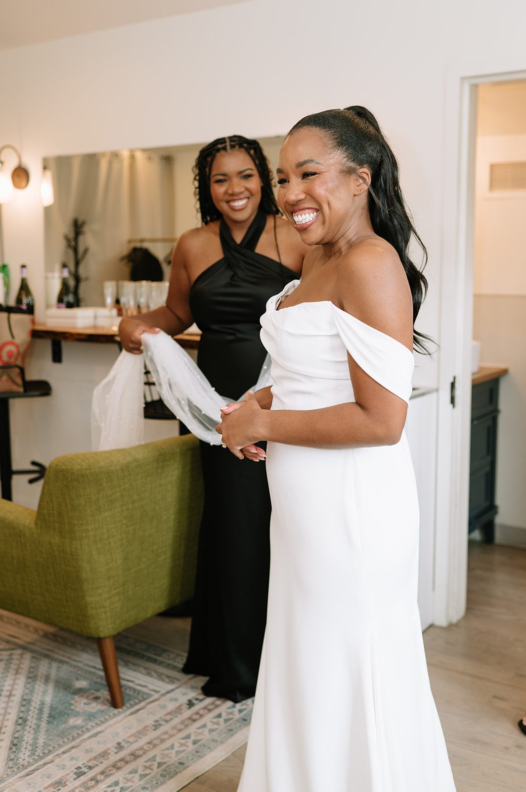 candid photograph of a bride and one of her bridesmaids smiling while getting ready for her north star gatherings idaho springs wedding