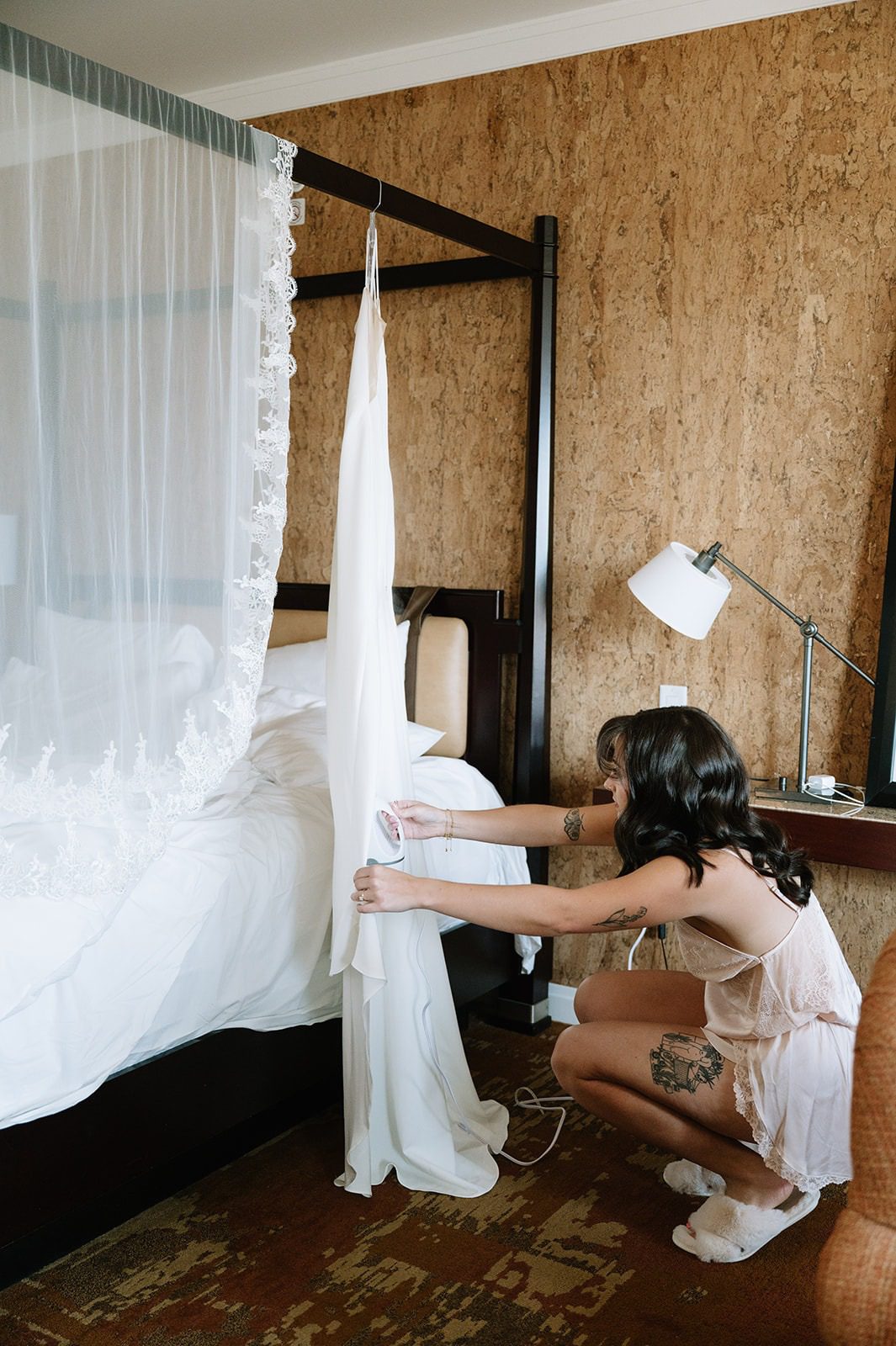 Bride steams her white wedding dress beside a hanging lace veil in a room at the St. Julien Hotel.